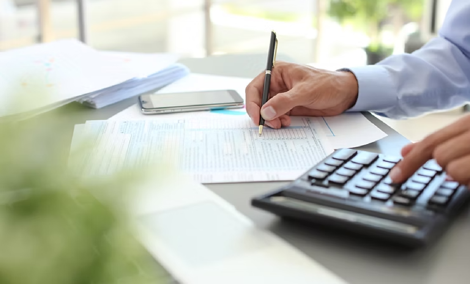 Mann rechnet am Taschenrechner und notiert Zahlen