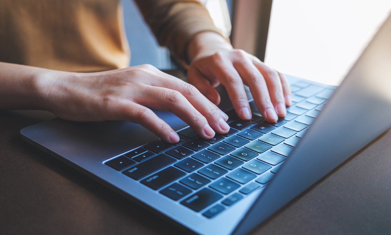 Person tippt auf einem Laptop